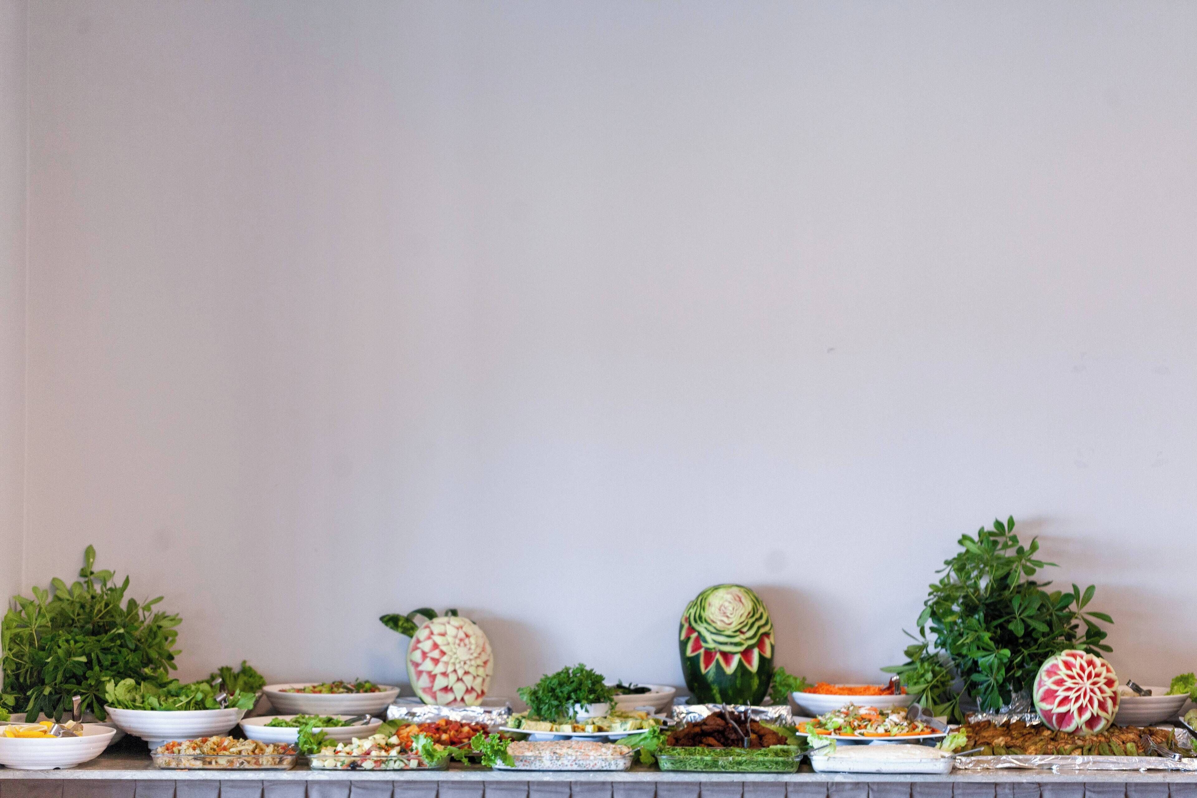 A buffet table with various dishes and a watermelon carved into a decorative piece.