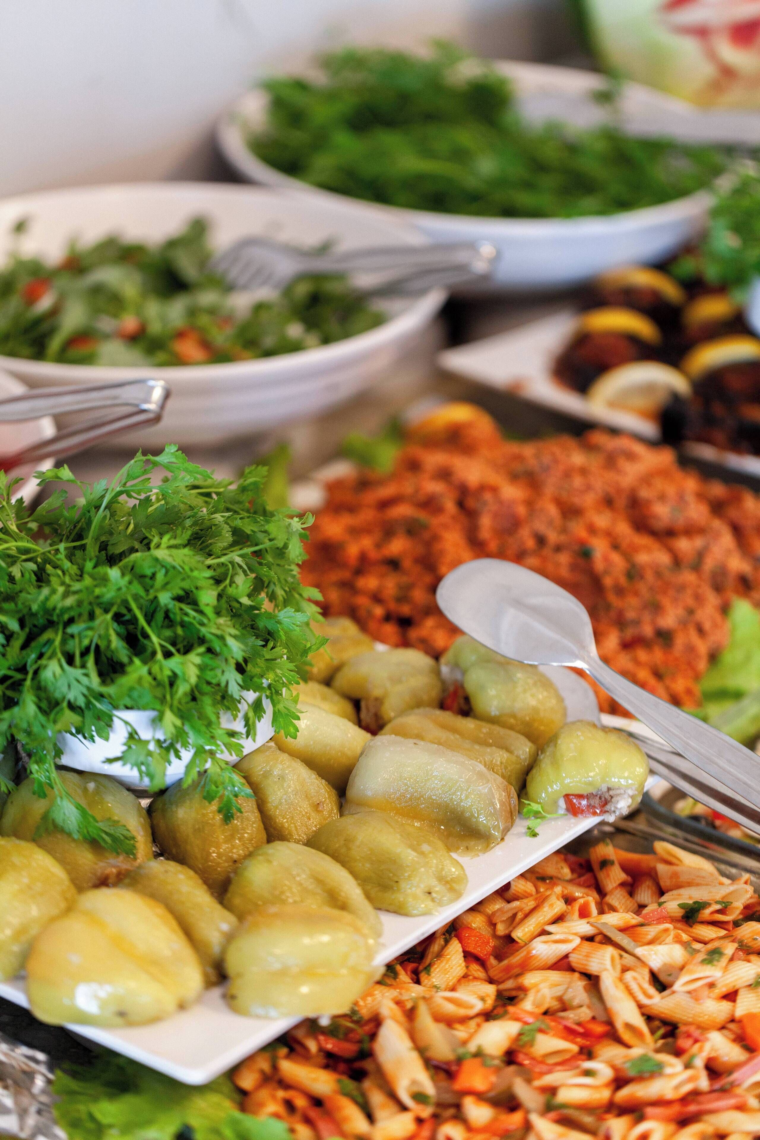 A buffet with various dishes including pasta, salads, and vegetables.