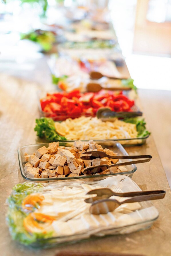 A buffet table with various food items including salads, meats, and vegetables.