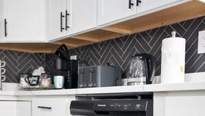 A modern kitchen with white cabinets, a stainless steel dishwasher, and a herringbone-patterned backsplash. - Charming Retreat w/ Pool Table in Chesterfield! (Chesterfield)