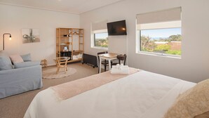 Una habitación de hotel con cama, escritorio, silla, armario y televisor.