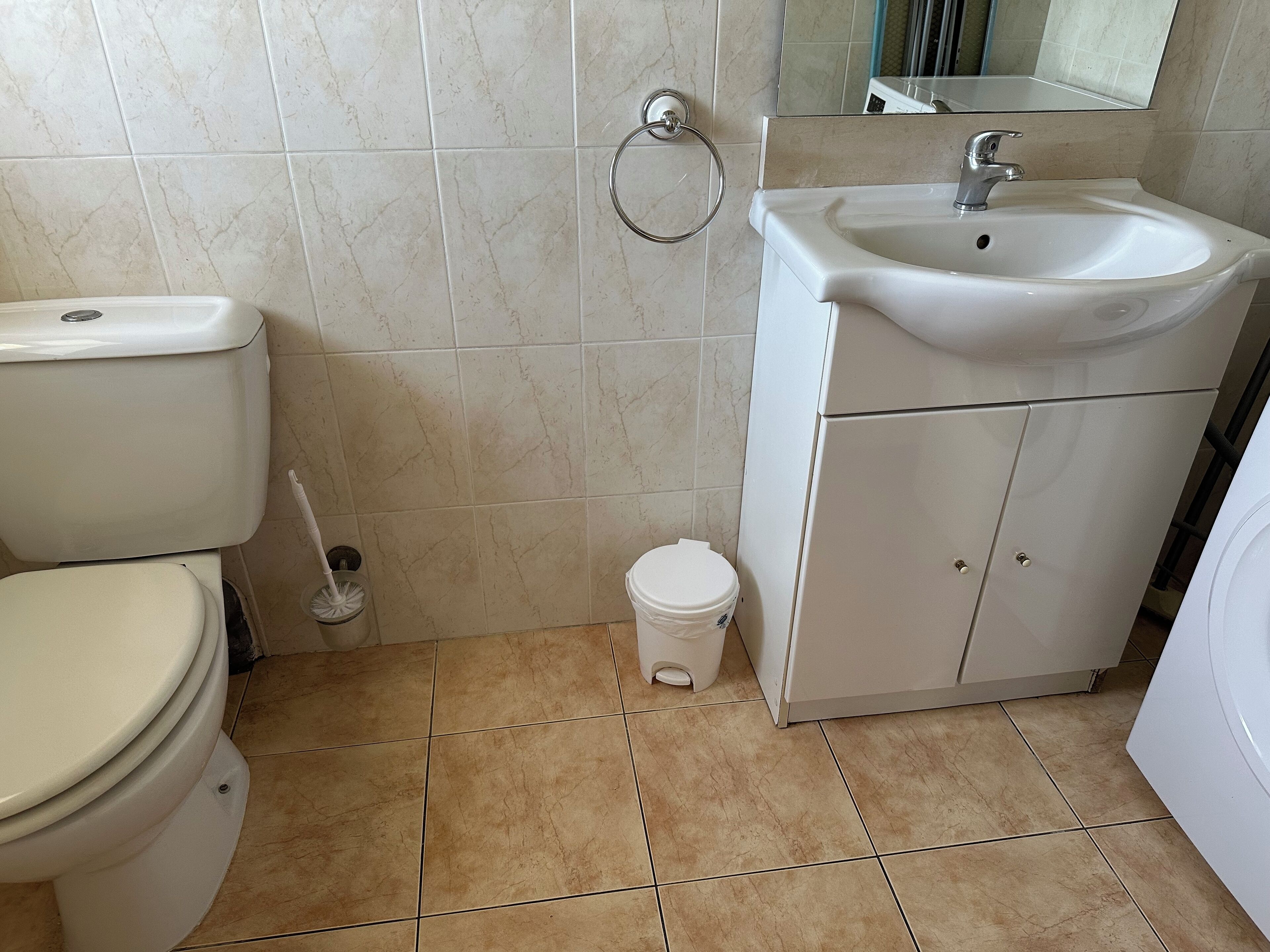 A bathroom with a toilet, sink, and small trash bin.