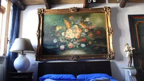 Een hotelkamer met een bed, een schilderij, een lamp en een beeld.