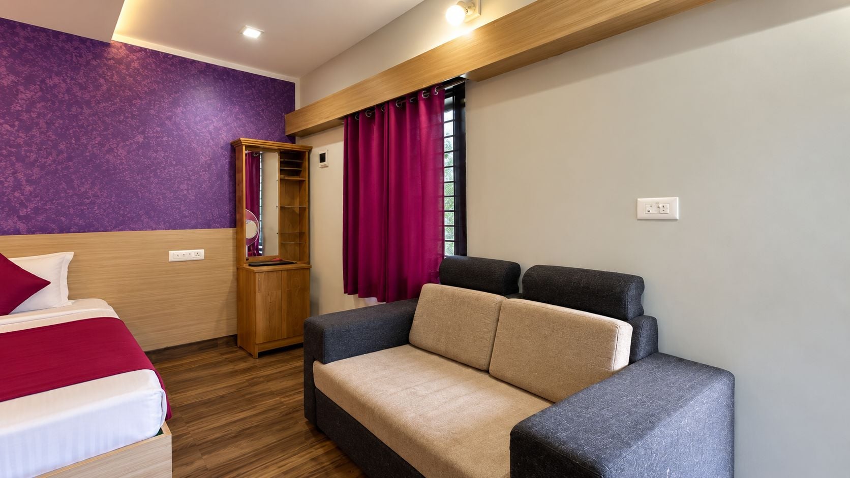 Una habitación con cama, sofá, armario de madera y ventana con cortinas.