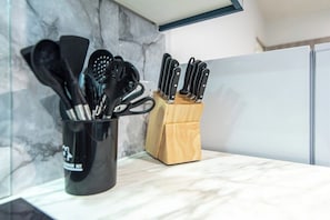 A kitchen counter with a utensil holder containing various kitchen tools and a knife block with knives.