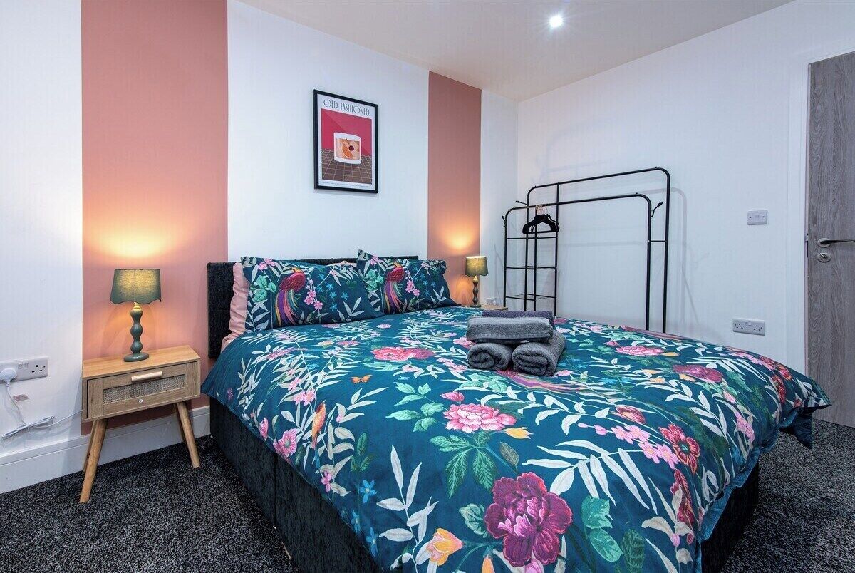A bedroom with a floral bedspread, a bunk bed, bedside lamps, and a framed picture on the wall.