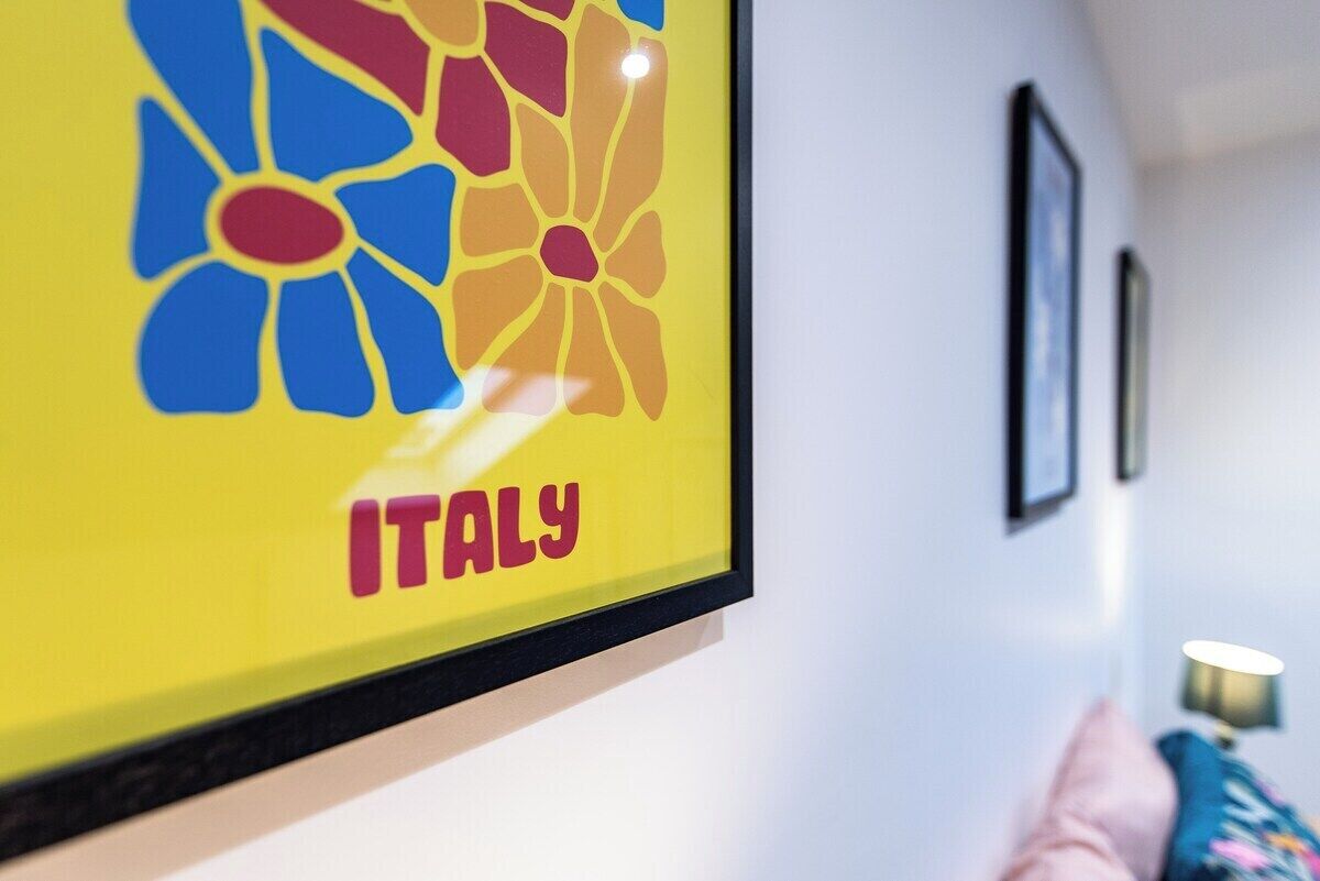 A framed artwork with a flower design and the word 'ITALY' on a wall.