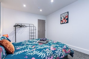Une chambre à coucher avec un lit, une armoire en métal, une porte et un tableau encadré au mur.