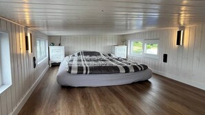 Une chambre avec un grand lit, des murs en bois et deux tables de chevet avec des lampes.