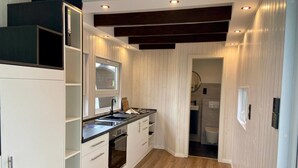 Une cuisine moderne avec des meubles blancs, un plan de travail noir et un four encastré.