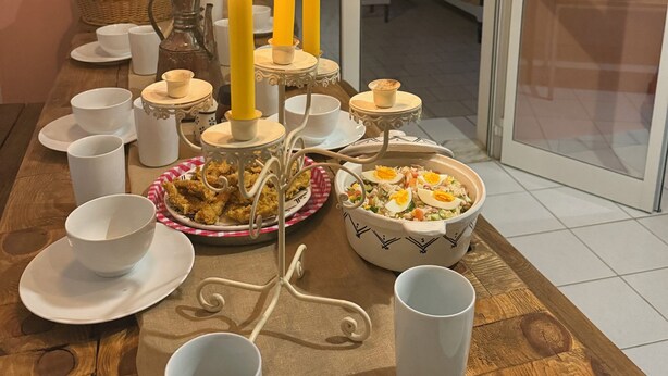 A dining table with white plates, cups, and a centerpiece of candles.