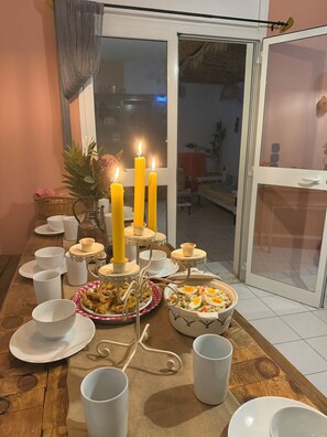 Une table à manger avec de l’assiette blanche, des tasses et un centre de table composé de bougies.