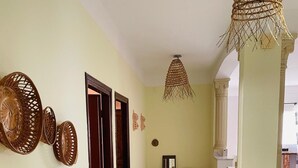A spacious hallway with a tiled floor, a hanging woven light fixture, and a door leading to another room.