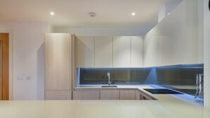 Een moderne keuken met een groot eiland, inbouwmeubels en een strak aanrecht.