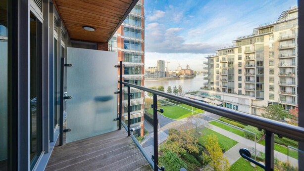 Een balkon met uitzicht op een rivier en moderne gebouwen.
