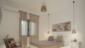 A bedroom with a bed, a chair, a bedside table, and a wall-mounted air conditioner.