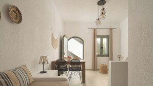 A modern room with a sofa, dining table, chairs, a mirror, and a hanging light fixture.