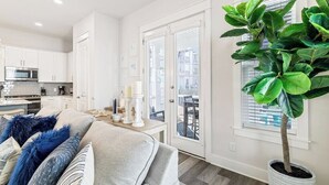 A modern kitchen with white cabinets, a microwave, and a dining area with a table and chairs.
