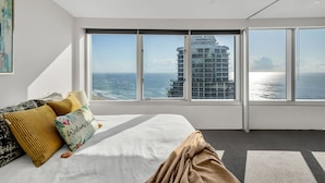 A modern hotel room with a large bed, a view of the ocean, and a high-rise building in the background. - Skyline on Gold Coast - Stunning Views -38th Floor (Surfers Paradise)