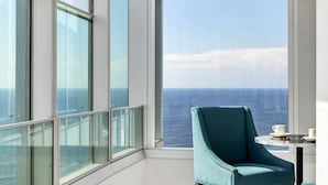 A modern room with large floor-to-ceiling windows, a teal armchair, and a small table with a cup and saucer. - Skyline on Gold Coast - Stunning Views -38th Floor (Surfers Paradise)