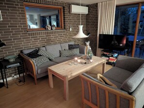 Un salon avec un canapé, une table basse, un téléviseur et un mur en briques.