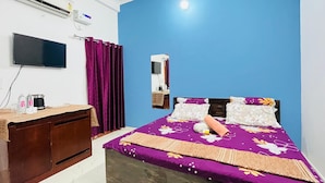 Een slaapkamer met een bed, een televisie, een bureau en een airconditioner.