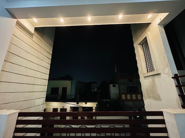 Vista nocturna de la entrada de un edificio con un banco al frente.