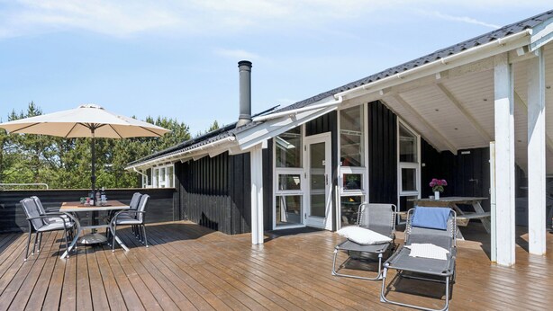 A wooden deck with a table and chairs, a covered seating area, and a chimney. - Cozy summer house near Hals (Hals)