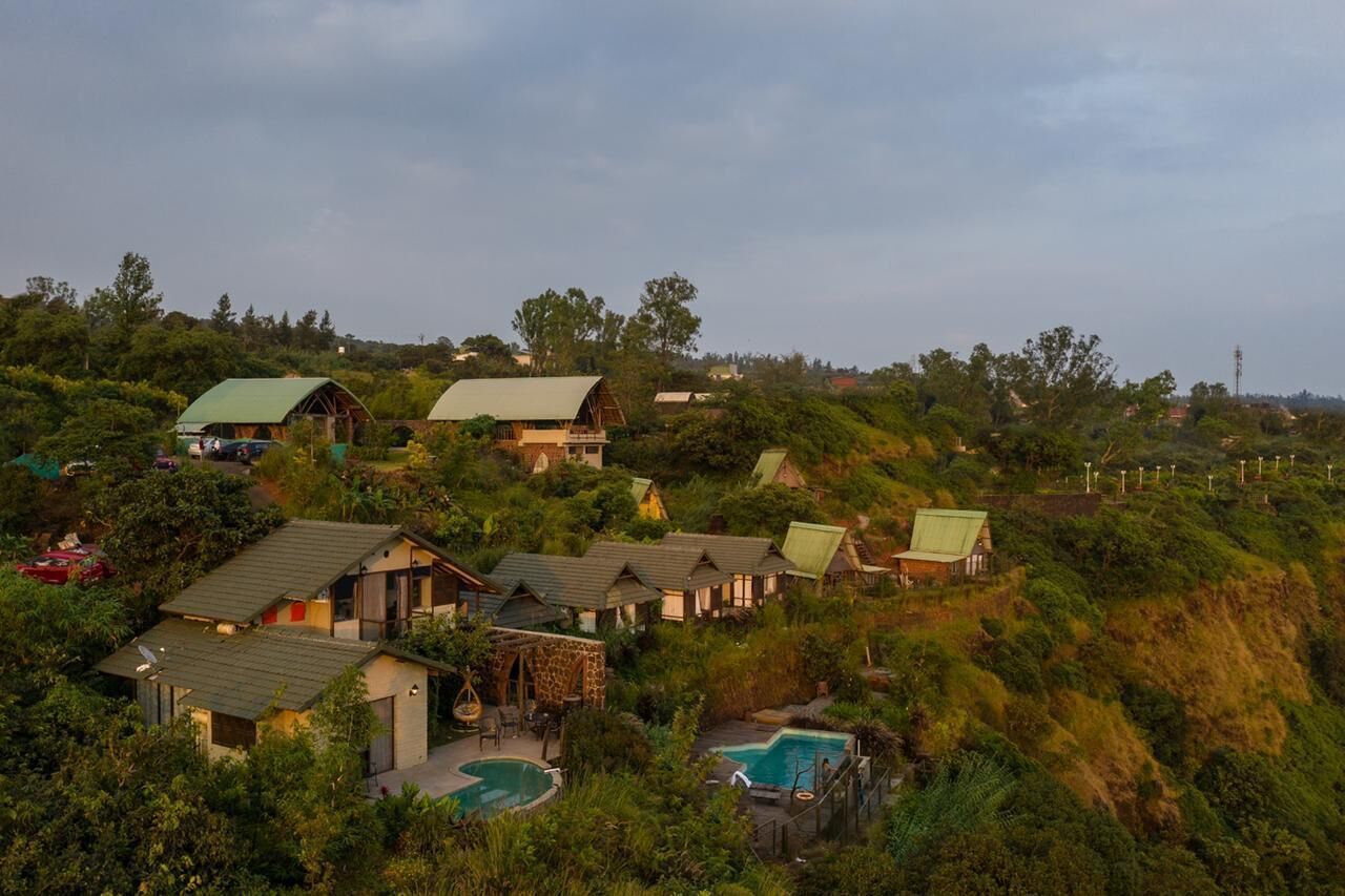 A hillside resort with multiple cottages, a swimming pool, and lush greenery.