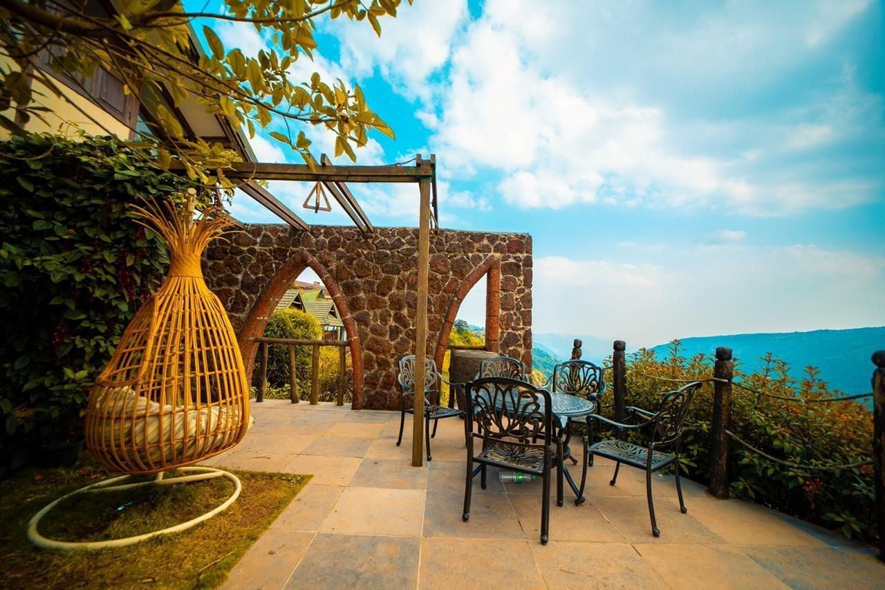 Un patio exterior con arcos de piedra, sillas de mimbre y una mesa.