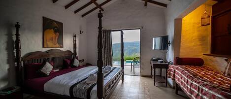 Un dormitorio con cama con dosel, una cama adicional, televisión y vistas al exterior.