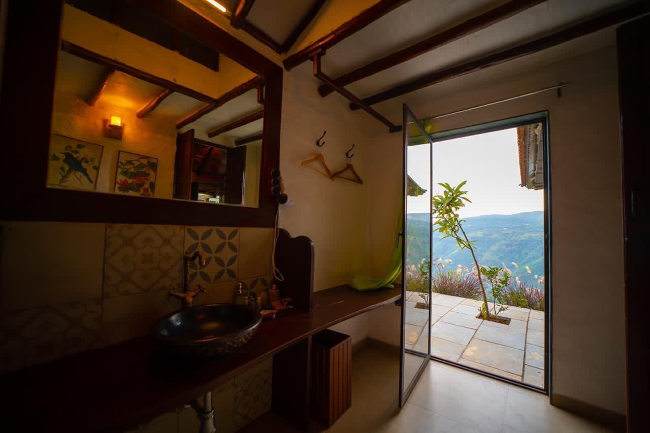 A bathroom with a large mirror, a sink, and a view of a balcony with plants.