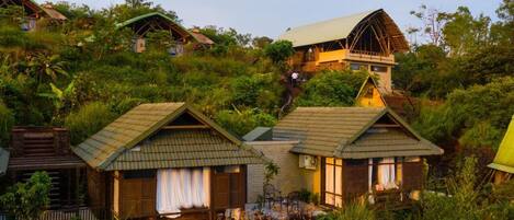 A hillside resort with multiple wooden cabins, each featuring a balcony and a small porch.