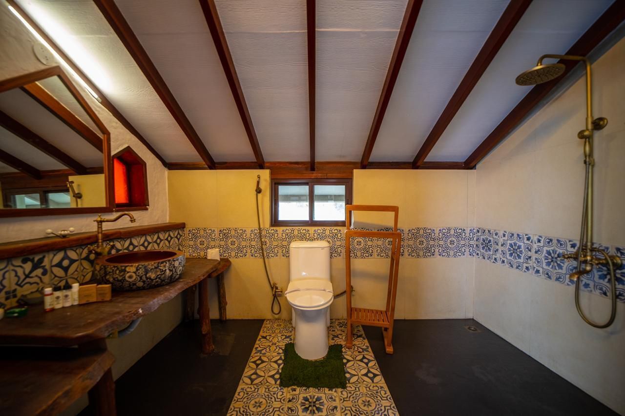 A bathroom with a wooden vanity, a large sink, a toilet, and a shower area.