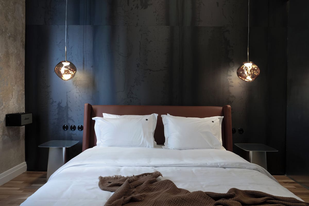 A modern bedroom with a large bed, two bedside tables, and two pendant lights.