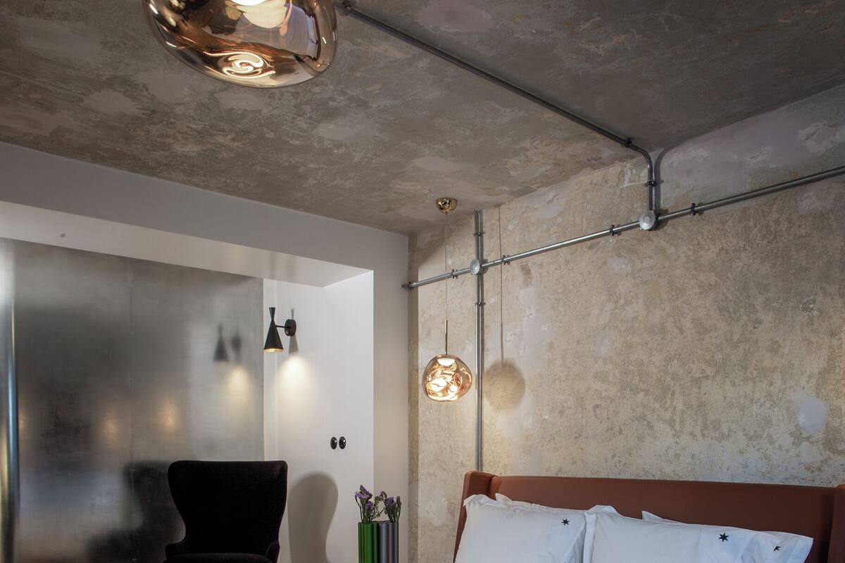 A modern bedroom with a large bed, a wooden floor, and a unique ceiling light fixture.