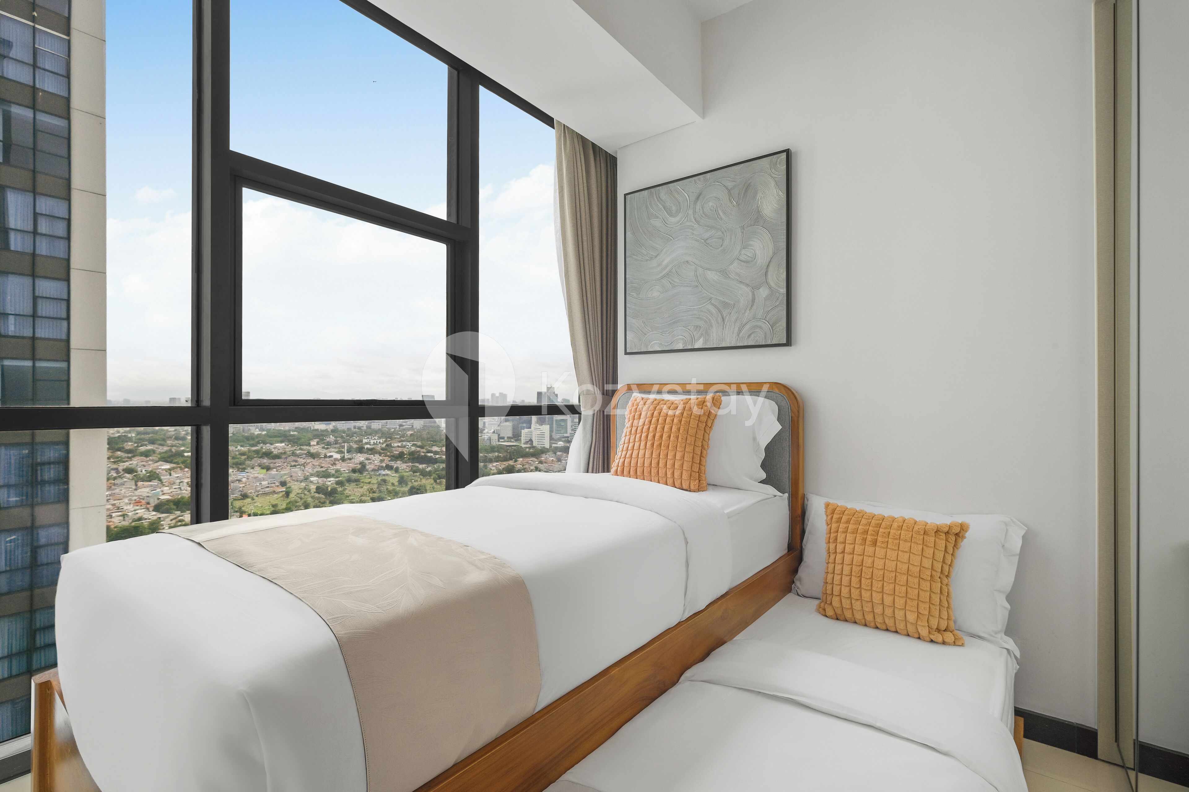 A modern hotel room with a large window offering a city view, a neatly made bed with white linens, and a single artwork on the wall.
