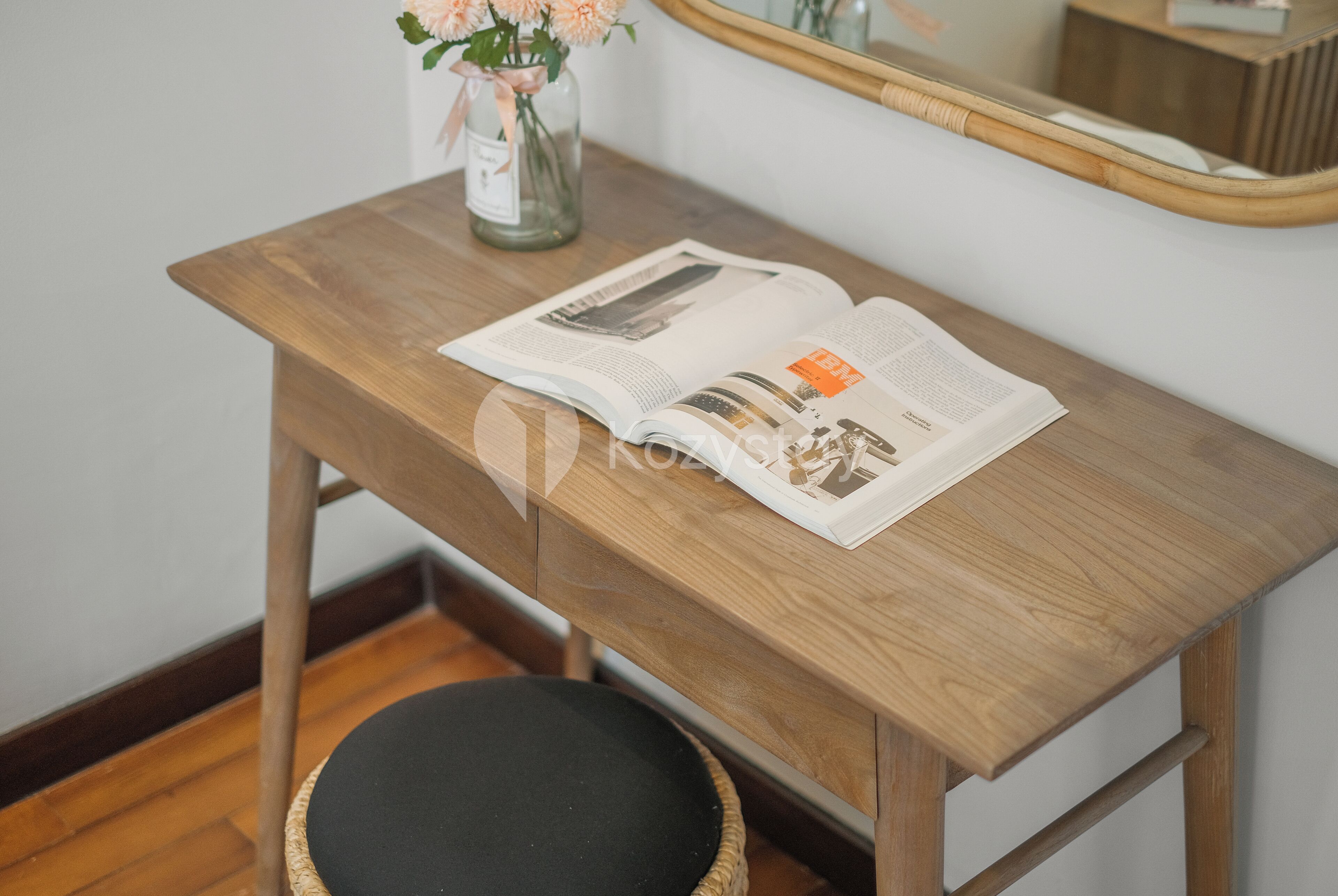 Un bureau en bois, un magazine, un vase avec des fleurs et un miroir.