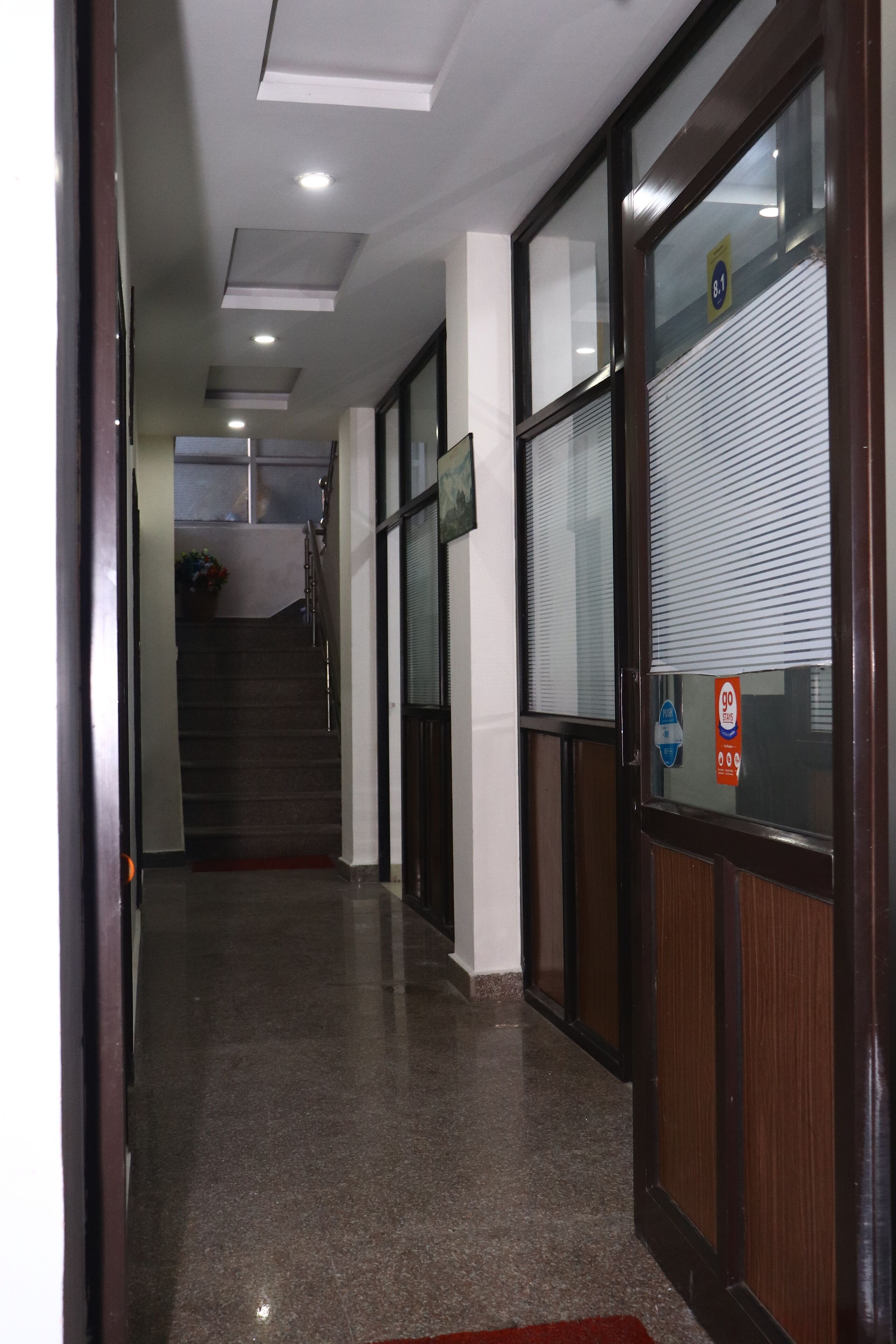 A hallway with a polished floor, a staircase, and a door with a window.