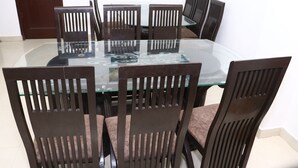 A dining table with six chairs, a glass top, and a wooden frame. - Hotel Hillora Mcleodganj (Dharamshala)