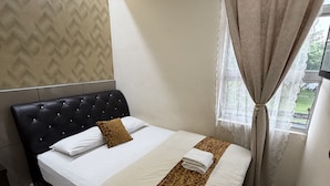 Een hotelkamer met een bed, hoofdeinde, raam met gordijnen en een kamer met een patroon.