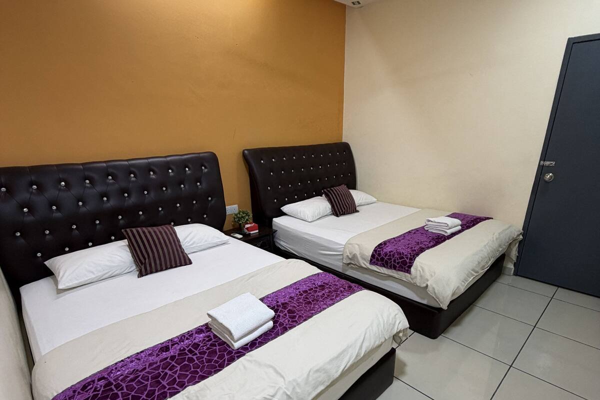 Habitación de hotel con dos camas, un ventilador de techo y una puerta.