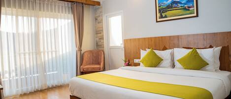A hotel room with a large bed, wooden headboard, a painting on the wall, and a window with curtains.