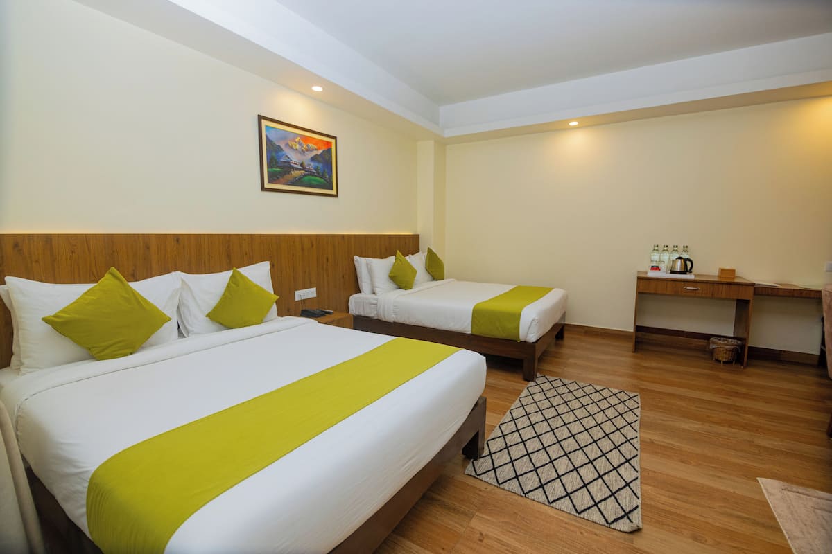 A hotel room with two beds, a desk, and a painting on the wall.