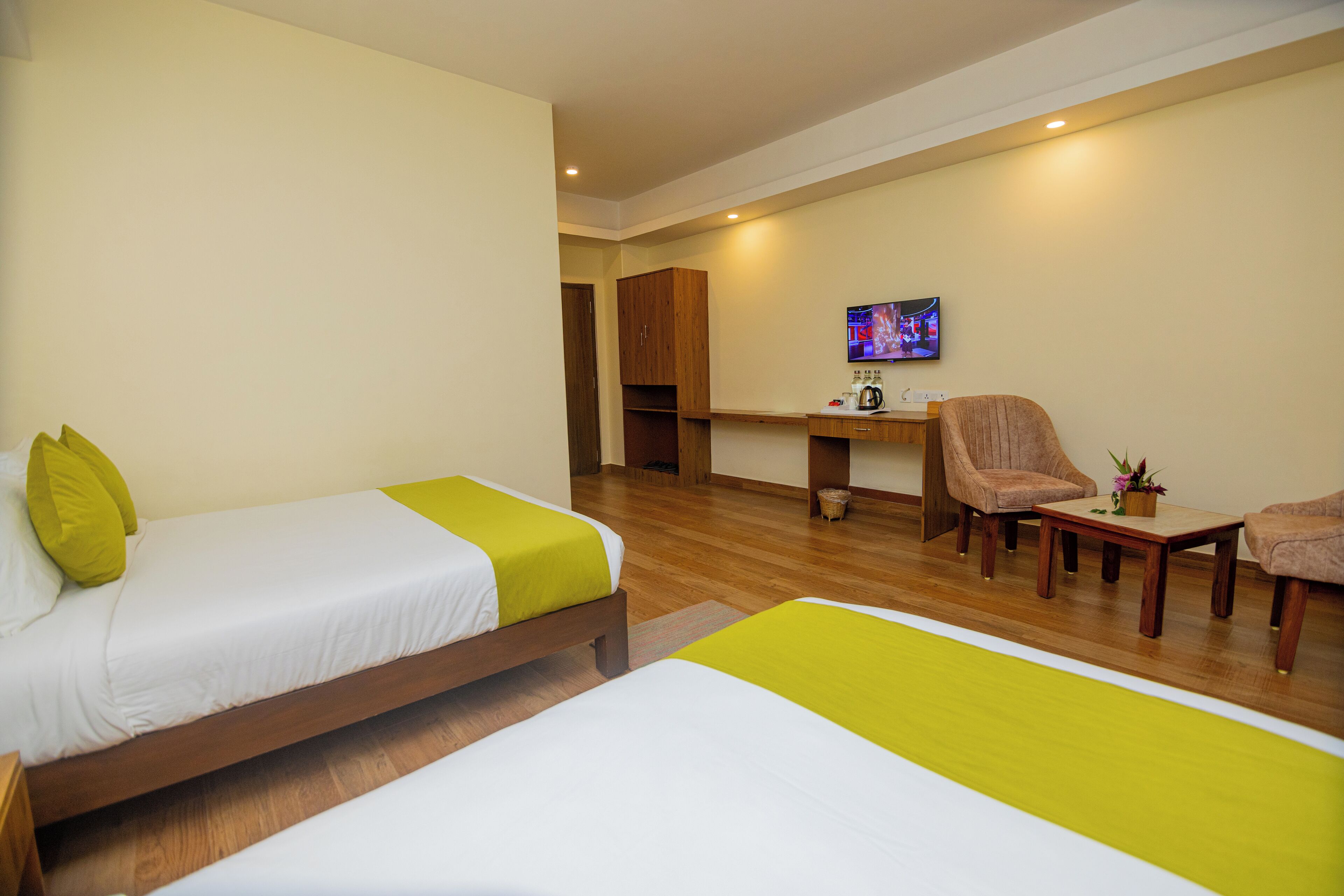 A hotel room with two beds, a desk, a chair, and a television.