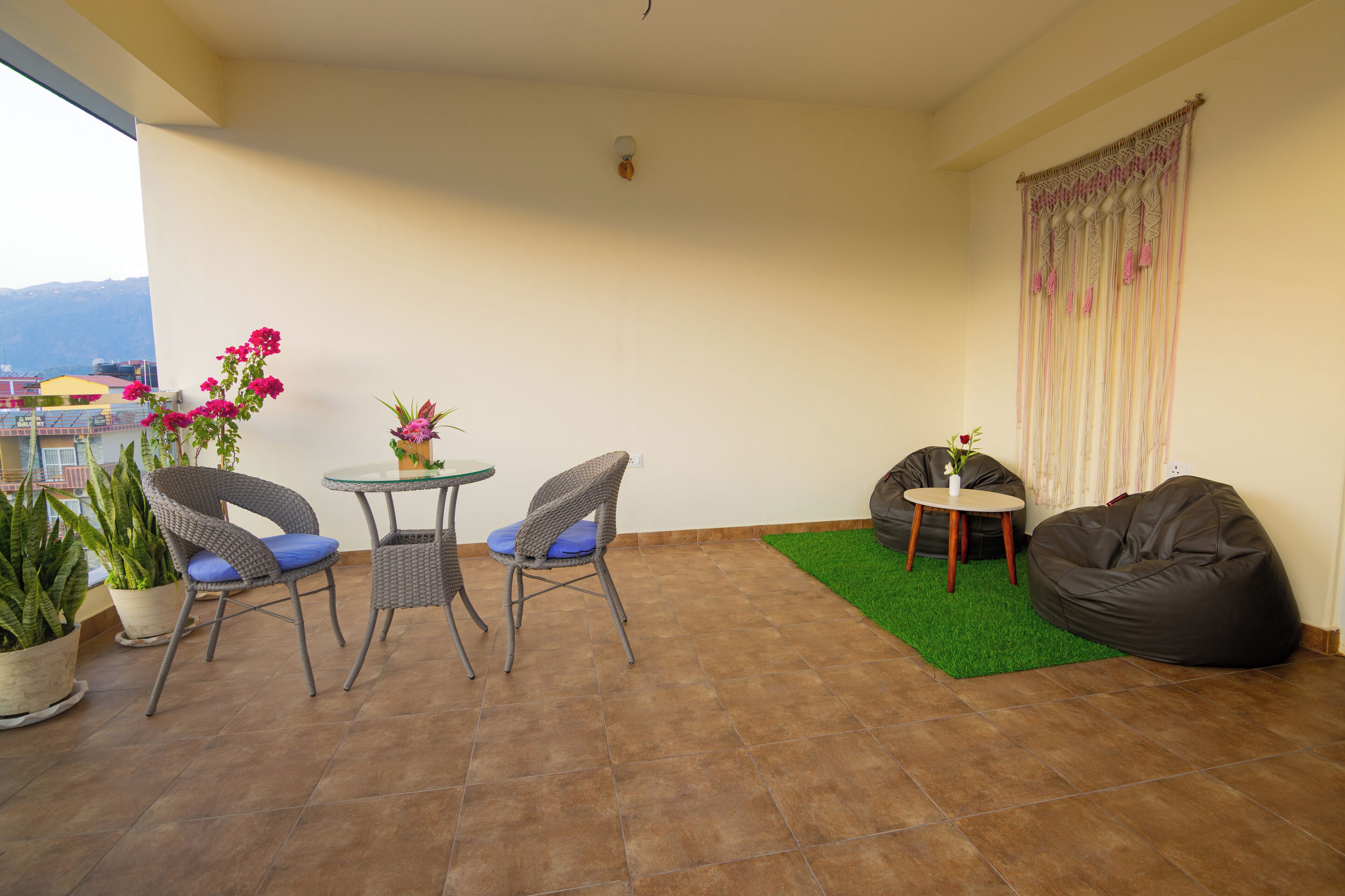 Ein Balkon mit Korbstühlen, einem kleinen runden Tisch, einem Sitzsack und Topfpflanzen.