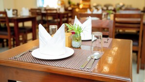 A dining table set with a white napkin, a glass, and a small vase with a plant.