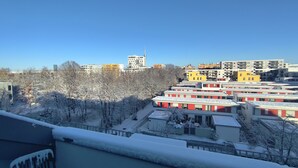 A residential area with multiple apartment buildings, some with snow on the roofs and trees.