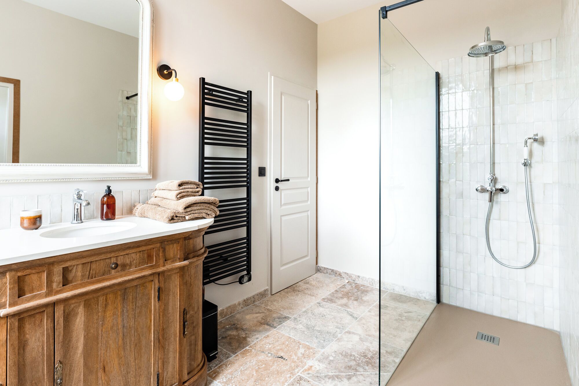 A bathroom with a wooden vanity, a glass shower enclosure, and a towel rack.