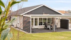 A modern house with a covered patio, a fenced yard, and a garage.